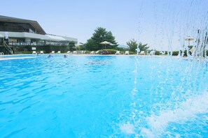 Een zwembad met helderblauw water, omringd door ligbedden en parasols.