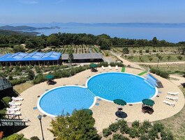 Un resort con dos piscinas grandes, sillas de descanso y vistas al mar.