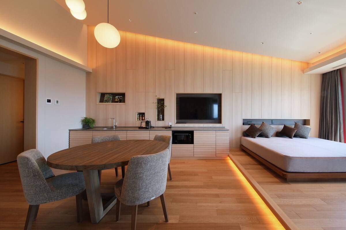 A modern bedroom with a large bed, a TV, and a dining area.