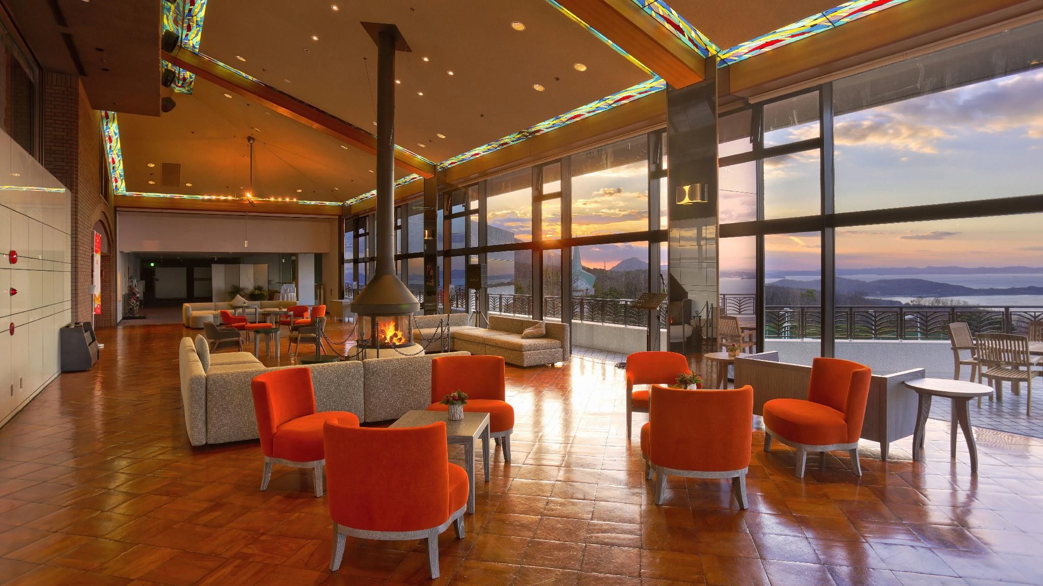 A spacious lounge area with a fireplace, comfortable seating, and large windows offering a scenic view.