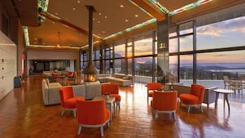 A spacious lounge area with a fireplace, comfortable seating, and large windows offering a scenic view.