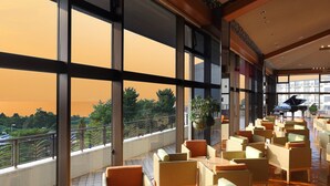 A spacious indoor area with large windows, multiple seating arrangements, and a piano.