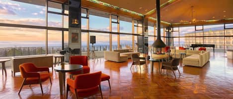 Un salon spacieux avec une grande baie vitrée, des sièges confortables et une cheminée.