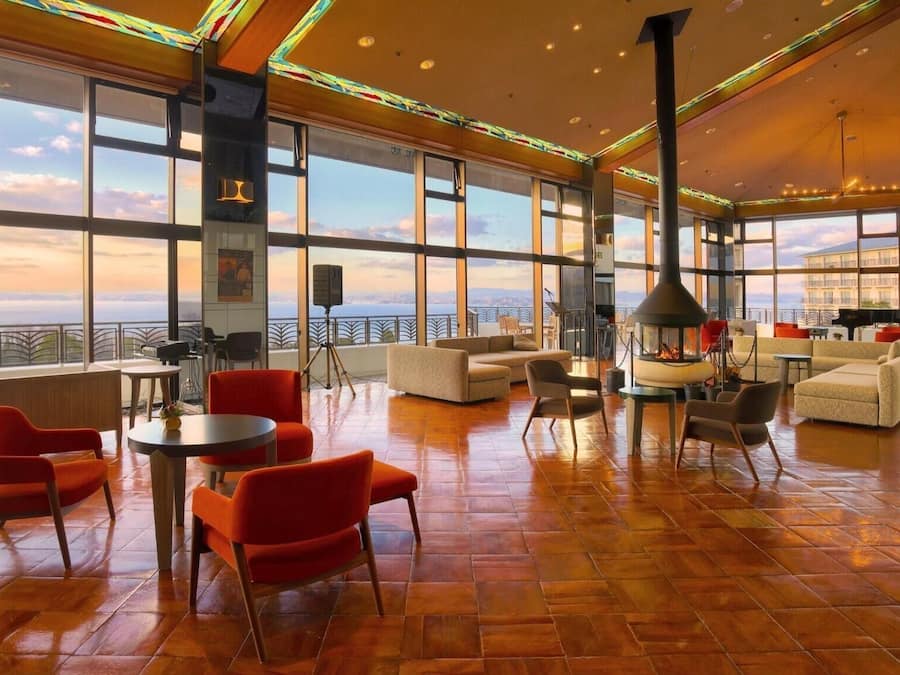 Un salon spacieux avec une grande baie vitrée, des sièges confortables et une cheminée.