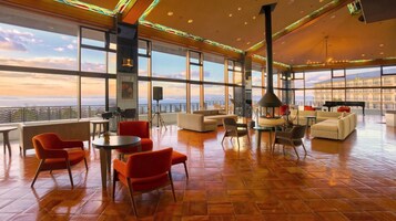 Un amplio salón con grandes ventanales, asientos cómodos y chimenea.