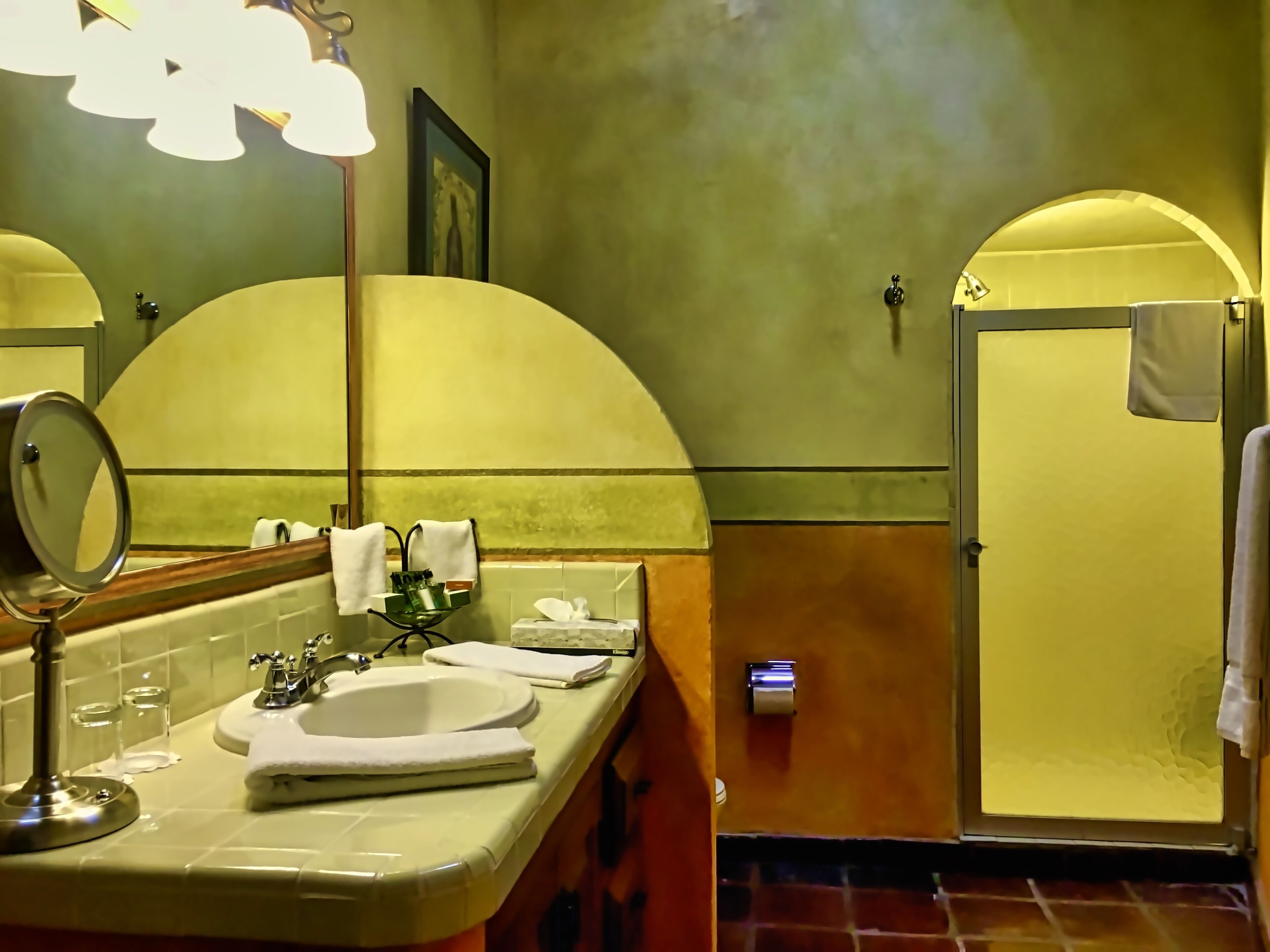 Un baño con lavamanos, espejo y toallero.