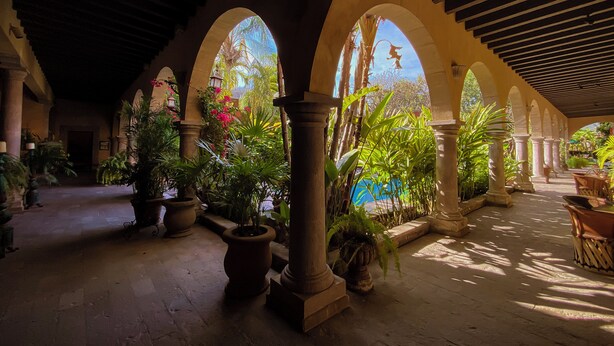 An indoor courtyard with arches, columns, and potted plants. - Hacienda de los Santos (Alamos)
