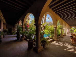 An indoor courtyard with arches, columns, and potted plants. - Hacienda de los Santos (Alamos)