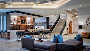 Un salón amplio con una cocina moderna, una escalera y una zona de estar con sofás.