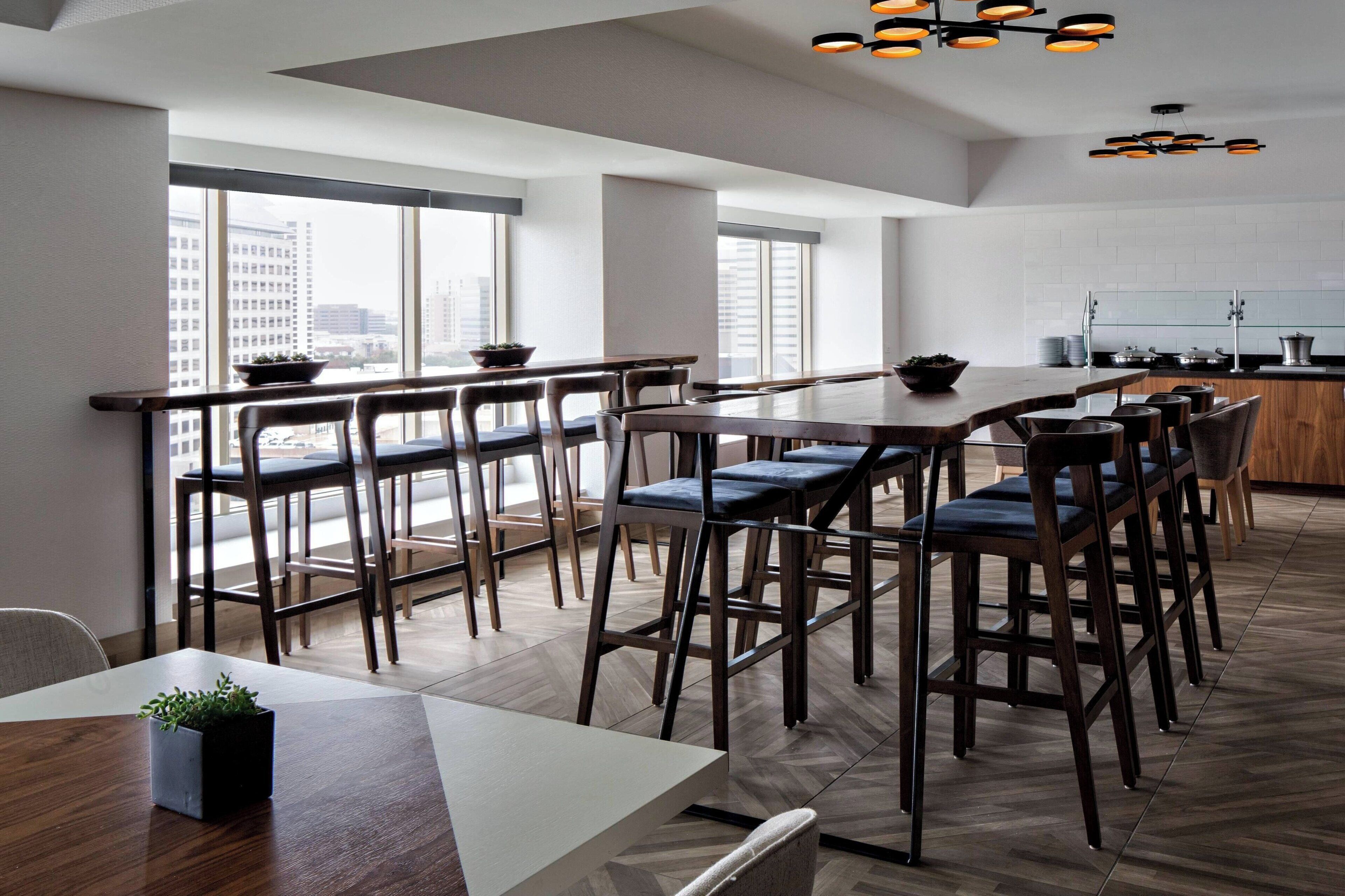 Una cocina moderna con una isla grande, asientos tipo bar y grandes ventanales que ofrecen vistas a la ciudad.