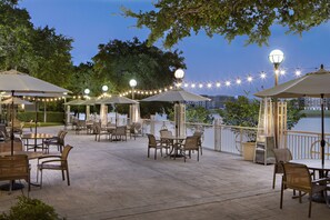 Une terrasse extérieure avec des tables et des chaises, des guirlandes lumineuses et des parasols.