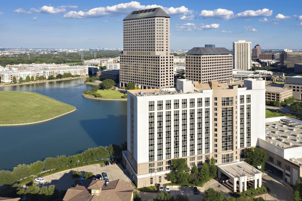 A high-rise building with a central courtyard and a lake in the background.
