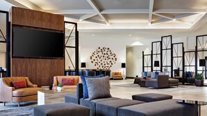 Amplia sala de estar con un televisor de pantalla plana grande montado en un panel de madera, varios sofás y una obra de arte decorativa en la pared.