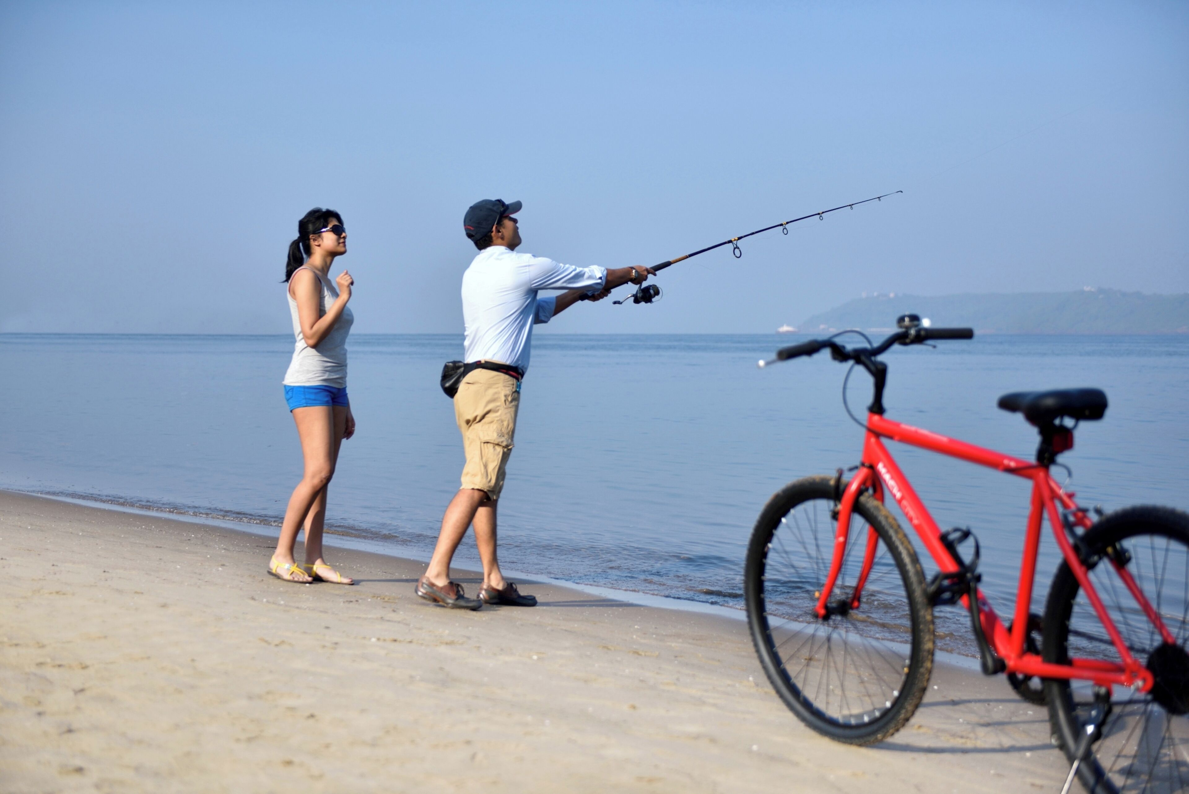 Un hombre y una mujer pescan junto al mar, con una bicicleta cerca.