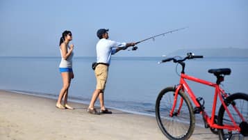 Un hombre y una mujer pescan junto al mar, con una bicicleta cerca.
