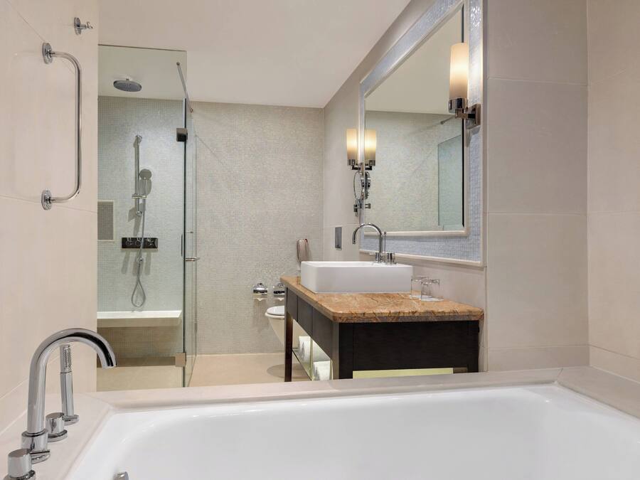 A modern bathroom with a large bathtub, a glass shower enclosure, and a vanity with a sink and mirror.