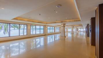 A spacious, modern hotel lobby with large windows offering views of palm trees and a beach.
