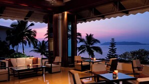 Un área de estar interior bien iluminada con vistas al océano al atardecer.