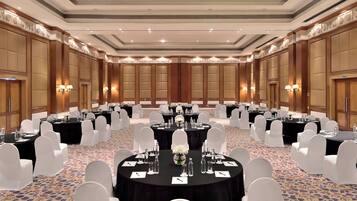 A large conference room with round tables, white chairs, and black tablecloths.