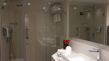 Ein modernes Badezimmer mit einer gläsernen Duschkabine, einem weißen Waschbecken und einem großen Spiegel.
