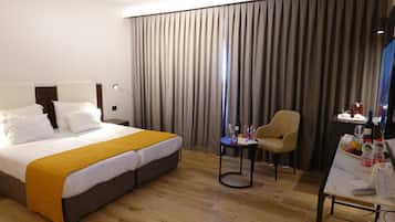 A hotel room with a large bed, a small table with a chair, and a desk with a chair.