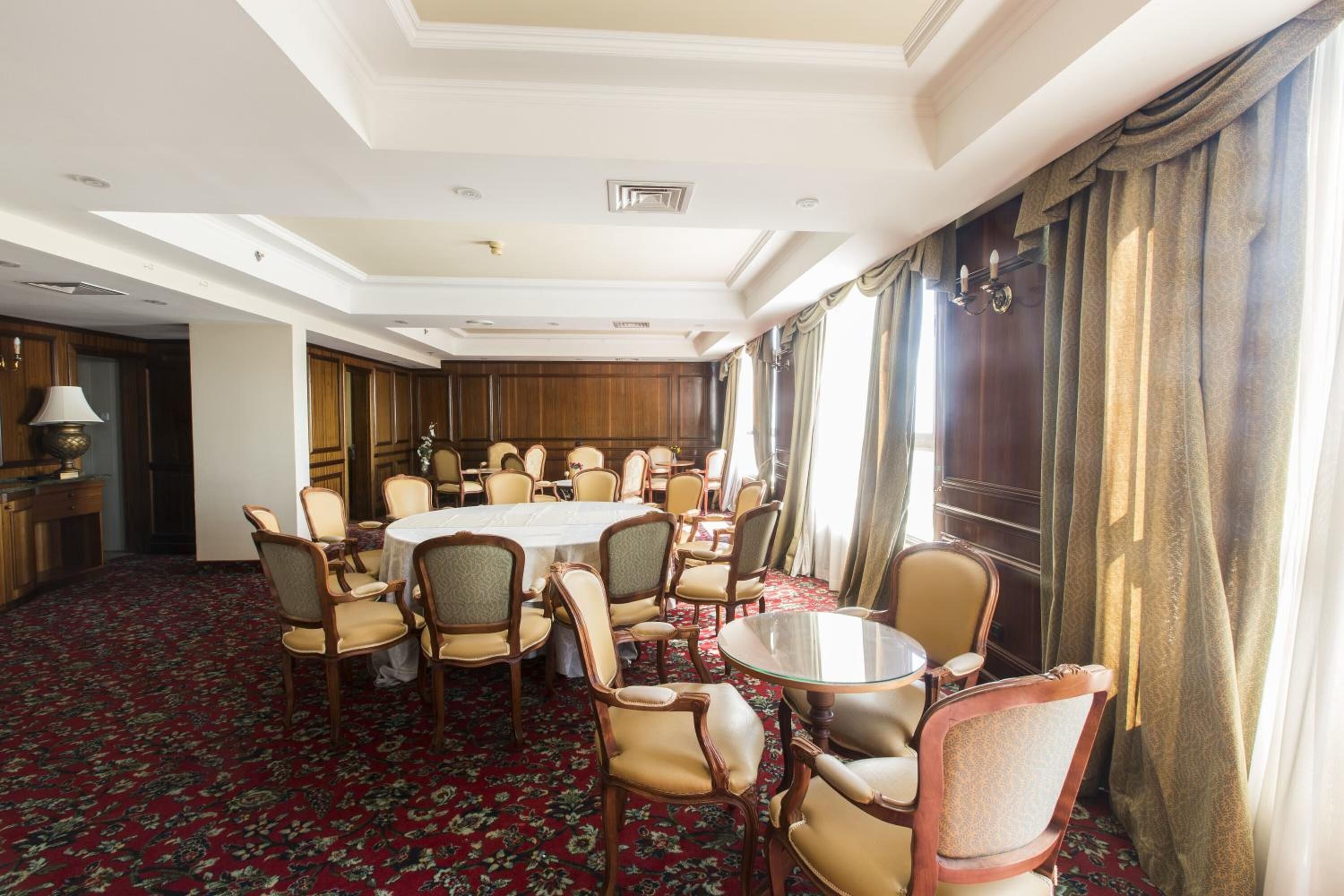 A conference room with a round table, multiple chairs, and a carpeted floor.