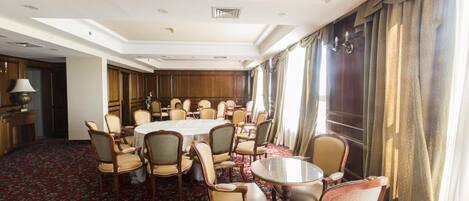 A conference room with a round table, multiple chairs, and a carpeted floor.