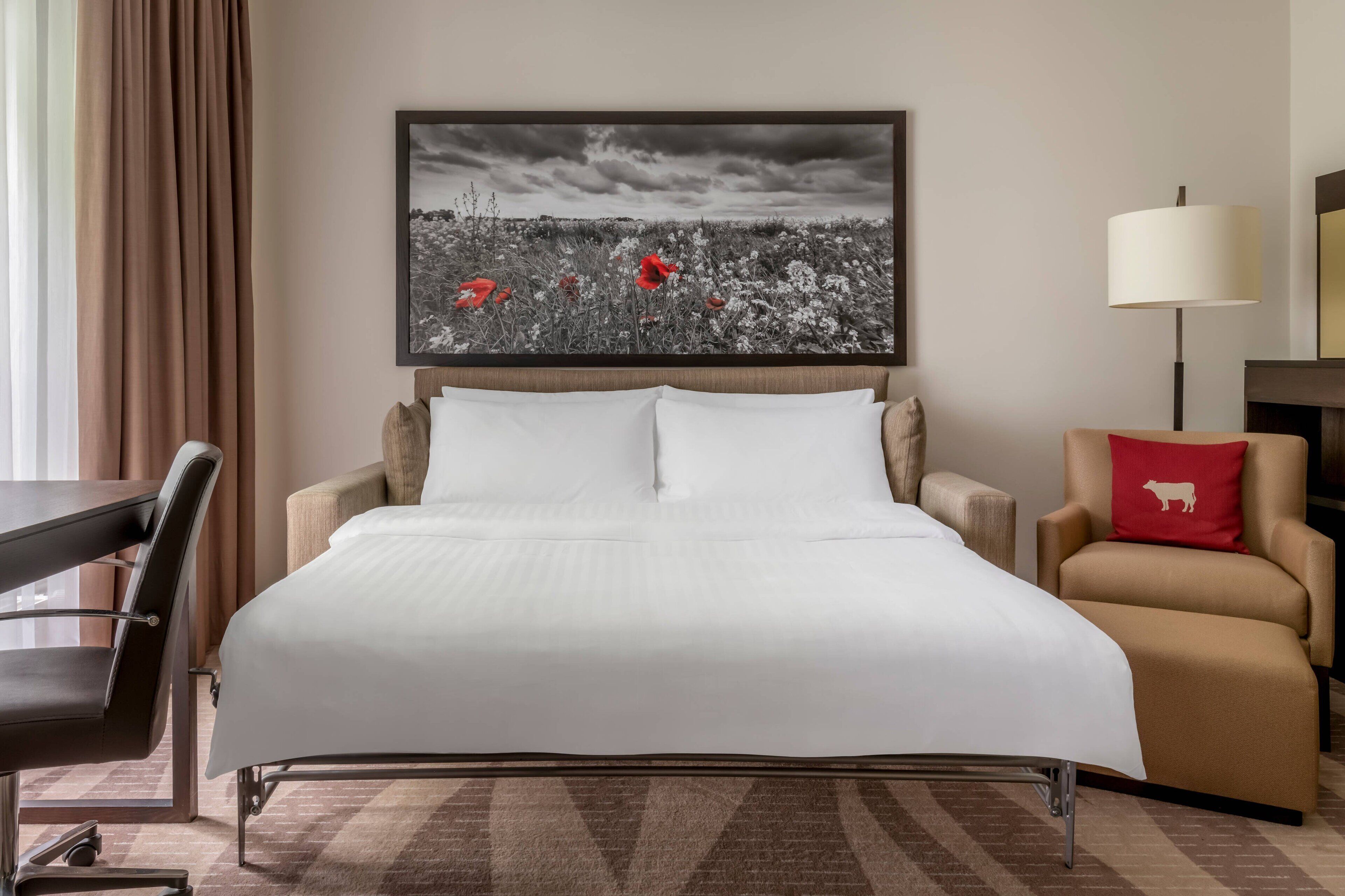 Una camera d'albergo con un letto grande, una scrivania, una sedia e una lampada.
