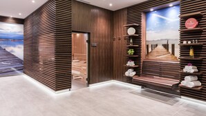 Un espace spa moderne avec un lambris en bois, une grande affiche représentant une plage et des étagères remplies de produits de toilette.