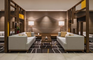 Un moderno vestíbulo de hotel con dos sofás enfrentados, una mesa de centro y un panel decorativo en la pared.