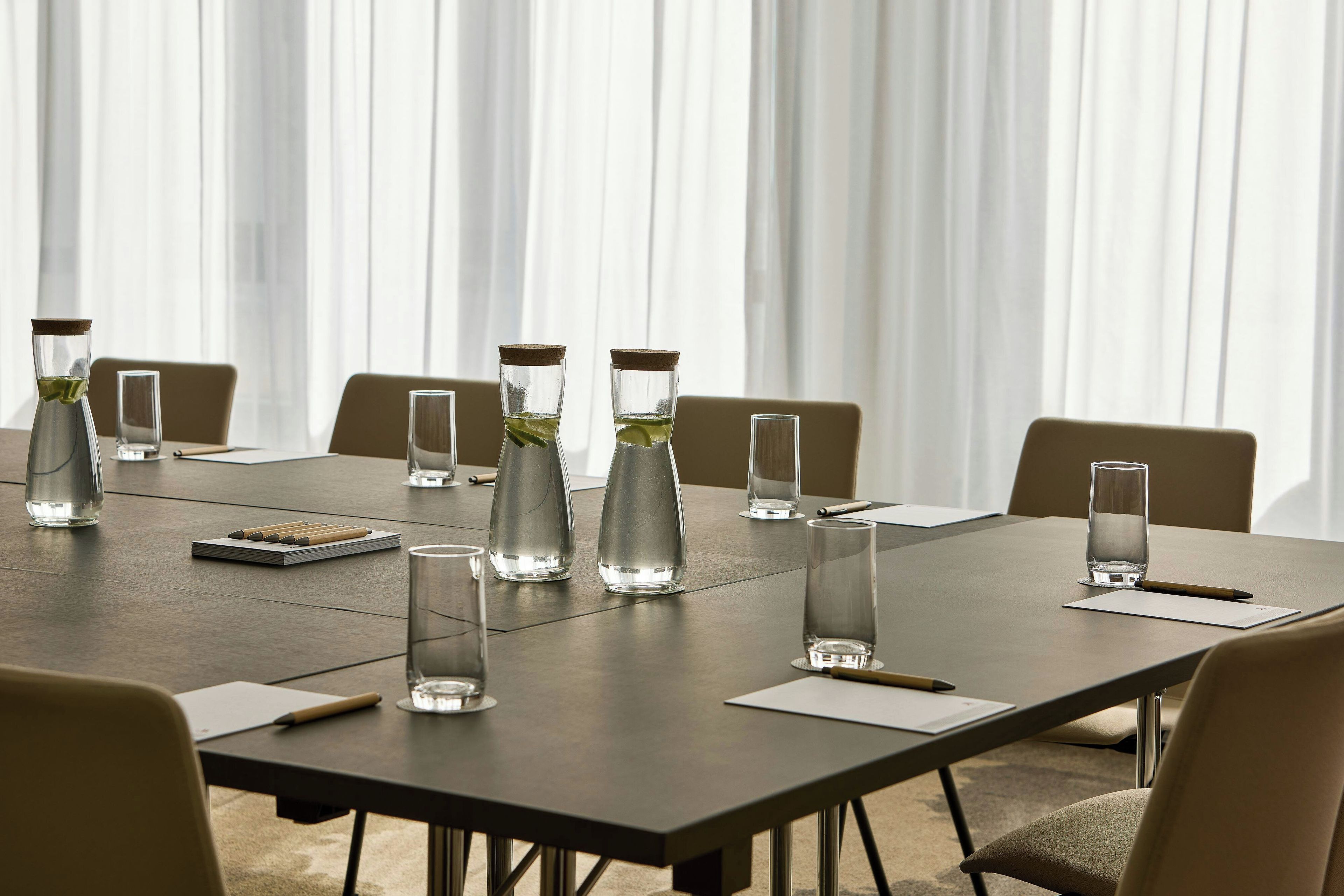 A conference table with water bottles, glasses, and pens.