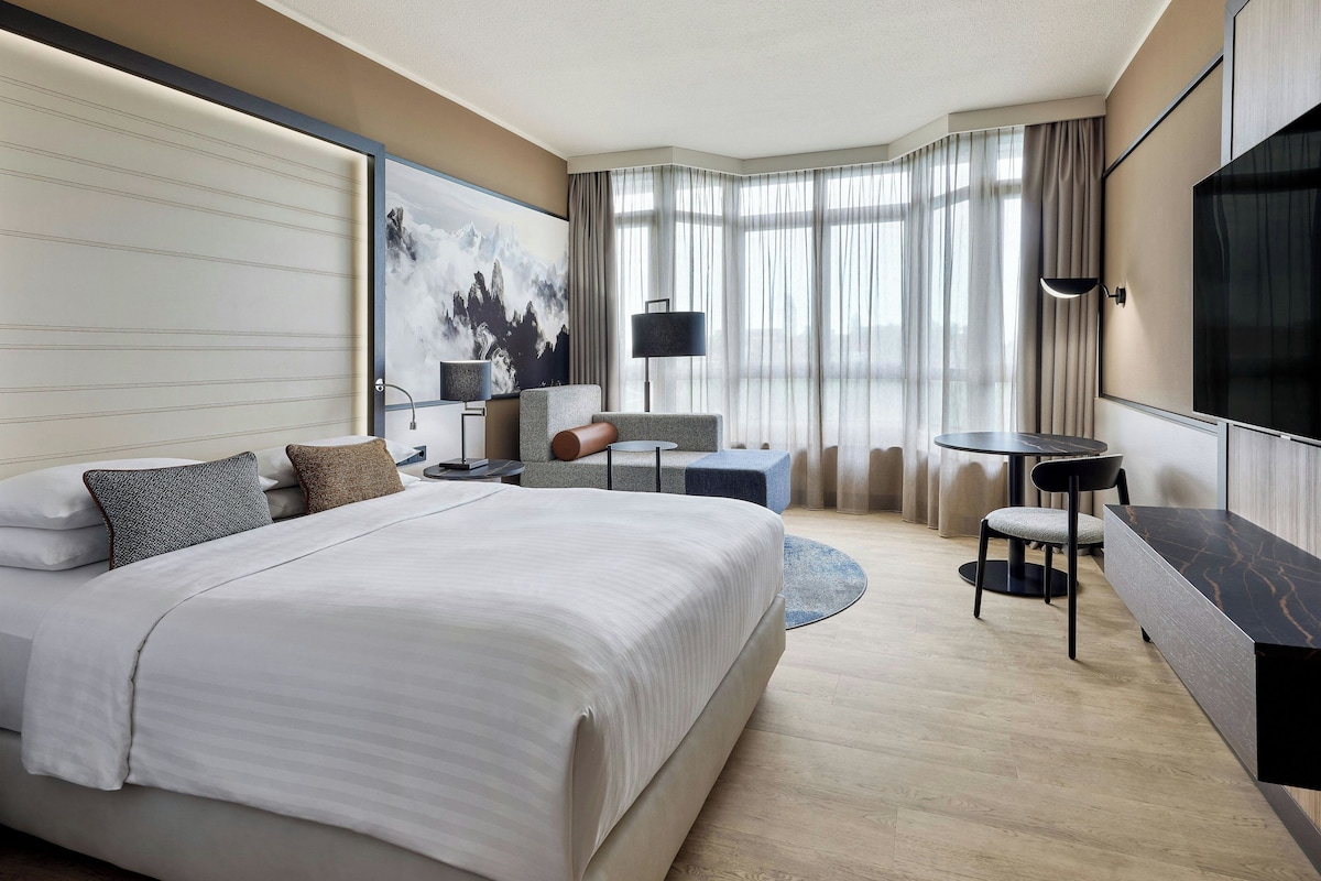 Une chambre d’hôtel avec un grand lit, un bureau, une chaise et un téléviseur.
