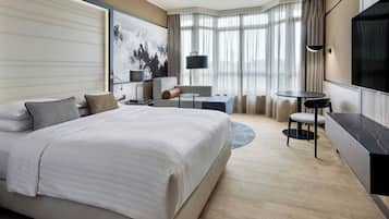 A hotel room with a large bed, a desk, a chair, and a TV.