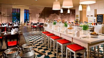 Un restaurante con piso a cuadros, taburetes rojos de bar y una larga barra con diferentes alimentos y bebidas.