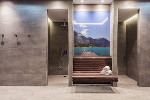 Un baño moderno con un banco, ducha y un gran mural de un lago y montañas.