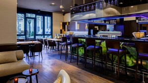 Un espace bar moderne doté d’un comptoir, de sièges et offrant une vue sur la ville grâce à de grandes fenêtres.
