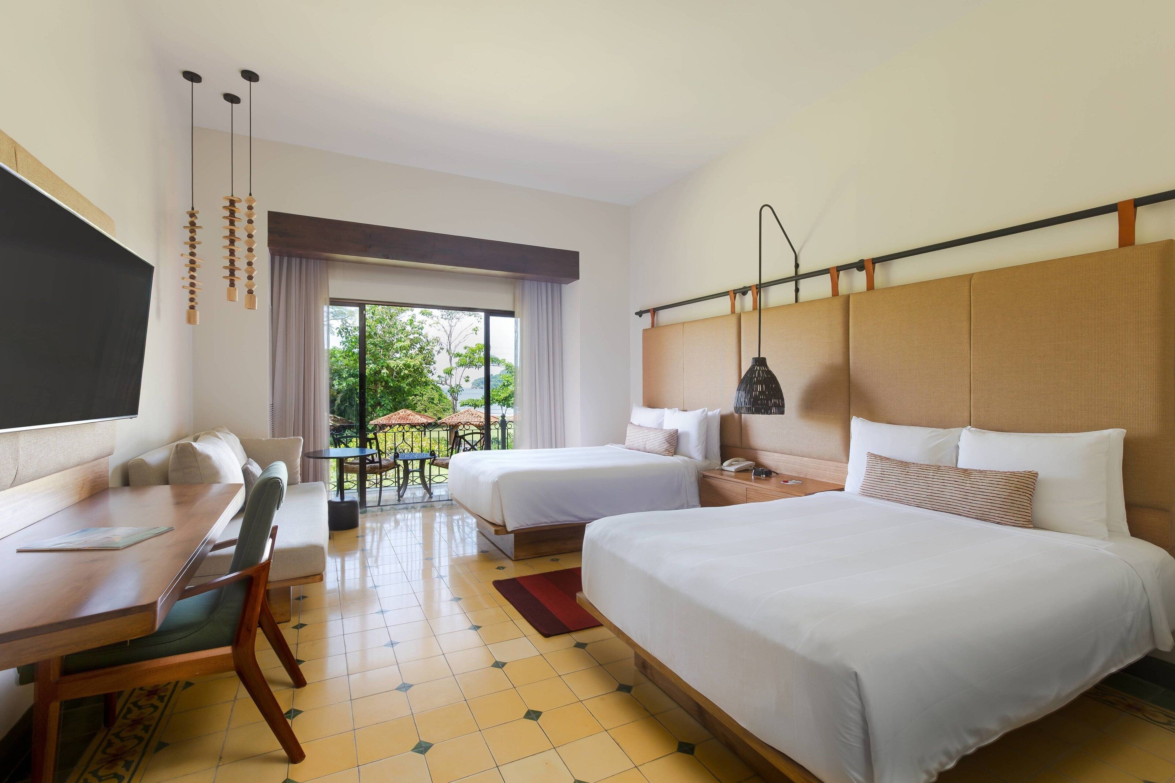 A hotel room with two beds, a desk, and a dining area.