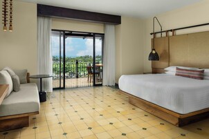 Una habitación de hotel con una cama, un sofá, una mesita y un balcón con vistas.