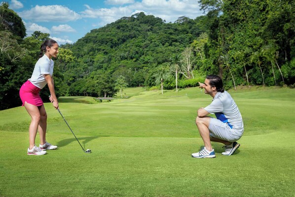 Un campo de golf con abundante vegetación y cielo despejado.