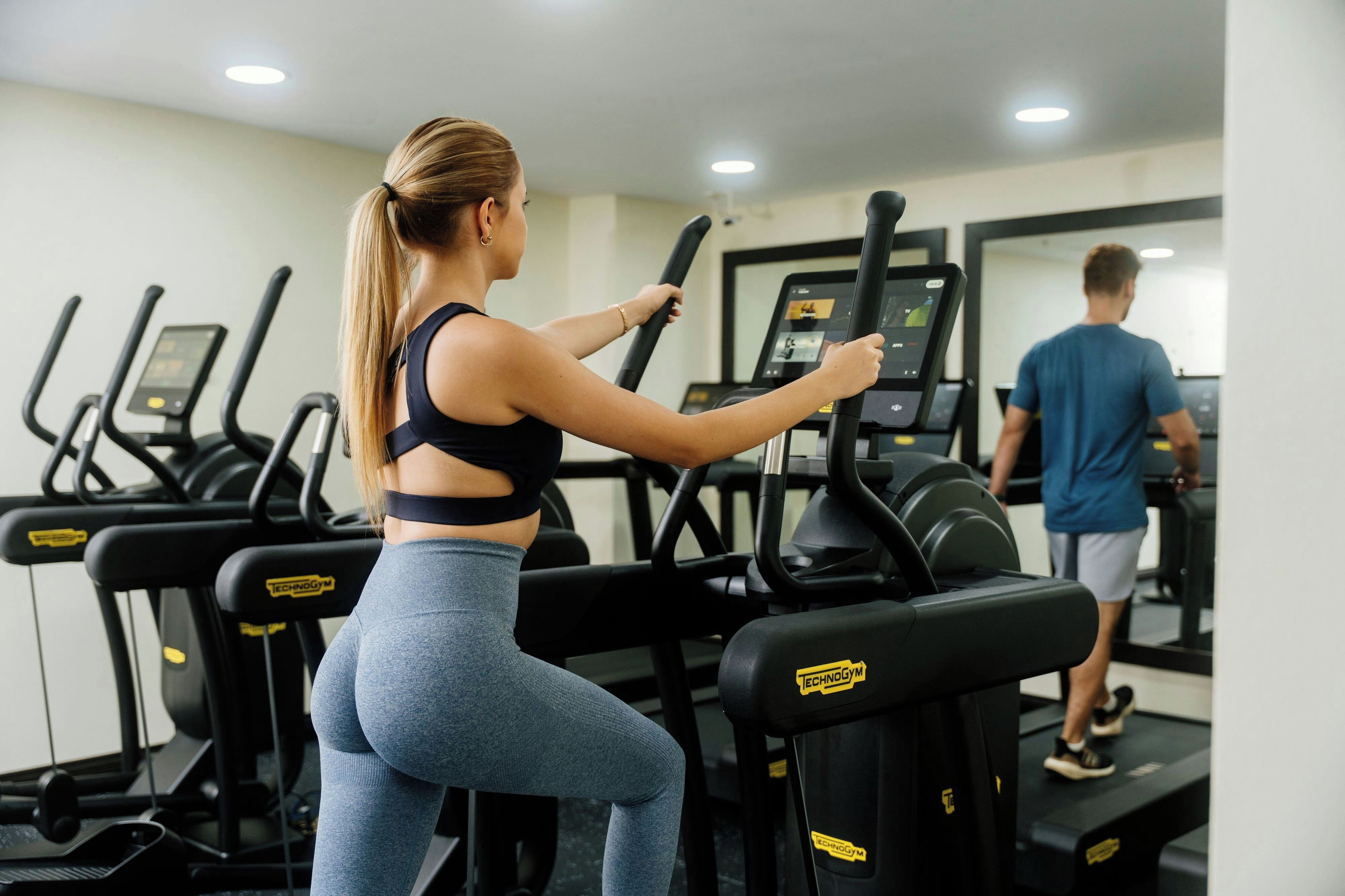 Gimnasio con cintas de correr y una persona usándola.