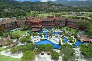 A large resort with multiple buildings, a central pool area, and surrounding greenery.