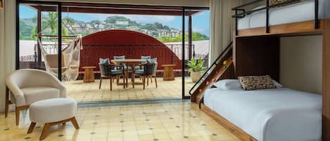 Ein Zimmer mit einem Etagenbett, einer Sitzecke mit Tisch und Stühlen sowie Blick auf eine Hügellandschaft.