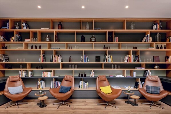 A modern library with leather chairs, wooden shelves, and books.