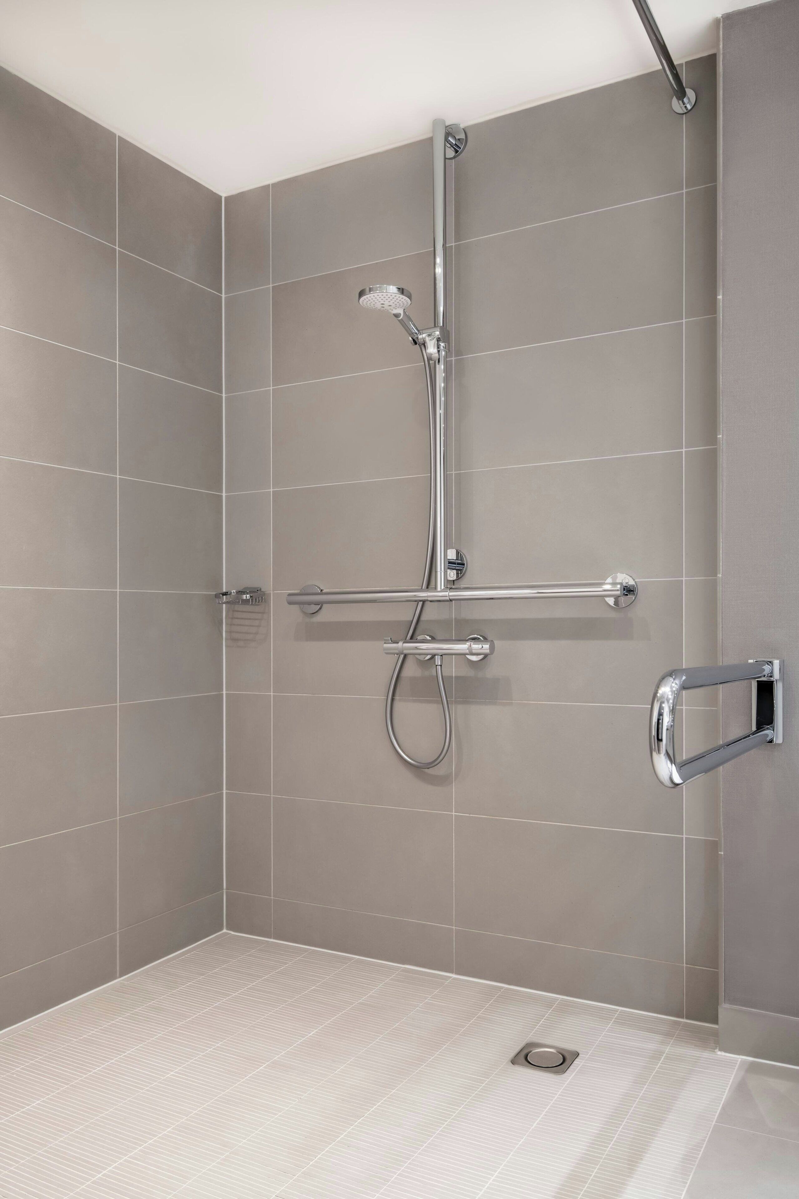 A modern shower with a handheld showerhead, a handheld showerhead, and a handheld showerhead.