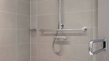 A modern shower with a handheld showerhead, a handheld showerhead, and a handheld showerhead.
