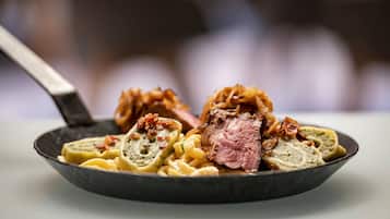 Un plato de comida con carne en rodajas, pasta y salsa.