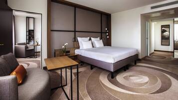 Una habitació d'hotel moderna amb un llit gran, un escriptori, una cadira i una taula petita.