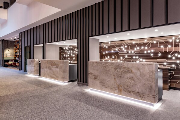 A modern reception area with marble reception desks, a patterned wall design, and a well-lit interior.