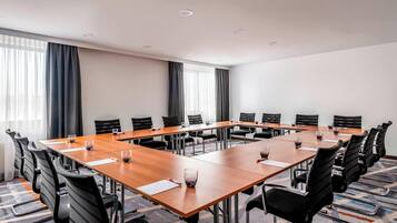 Ein Konferenzraum mit langem Tisch, schwarzen Stühlen und Gläsern.