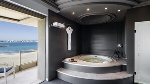 A modern bathroom with a jacuzzi, a robe, and a view of the beach. - Mövenpick Hotel & Casino Malabata Tanger (Tangier)